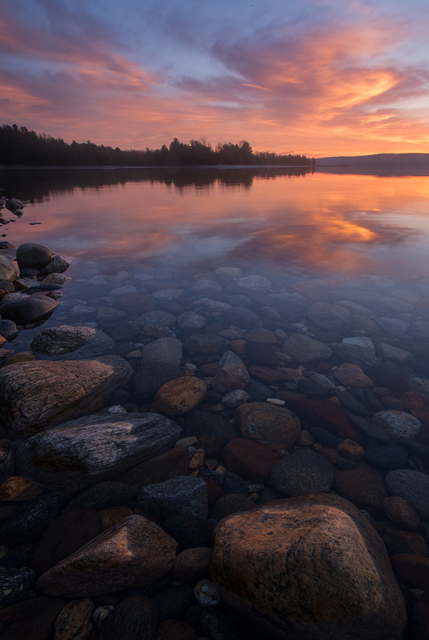 A simple sunrise reflection with the forground rocks catching the beautiful light and colors.